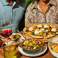 Table filled with plates, pizza, and a glass of wine