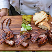 BBQ Ribs and bread on a board presented by a chef