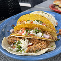 Three tacos with meat, cheese, and cilantro