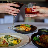 Two Glasses cheering with plates of fine dining below