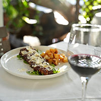 A plate with steak and potatoes and a glass of wine