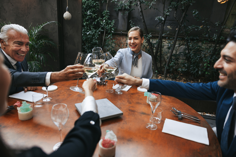 Group of four business diners out to lunch, clinking wine glasses