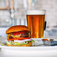 A Cheeseburger and a glass filled with beer